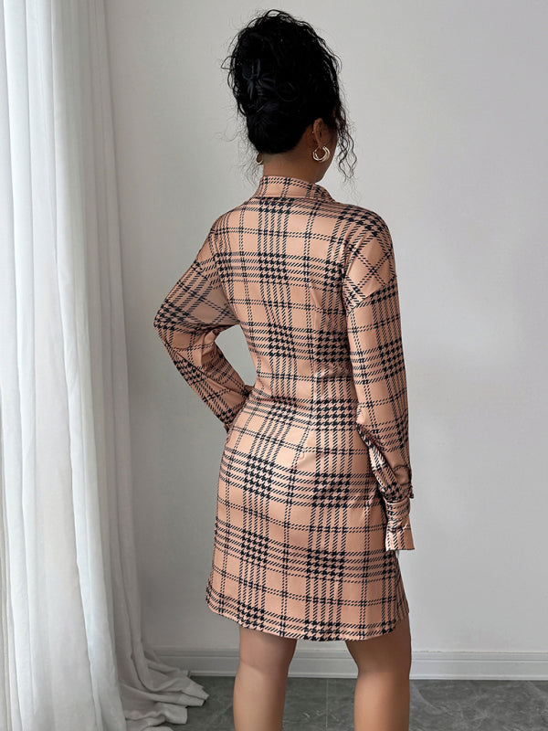 Person wearing a plaid dress standing against a white wall.