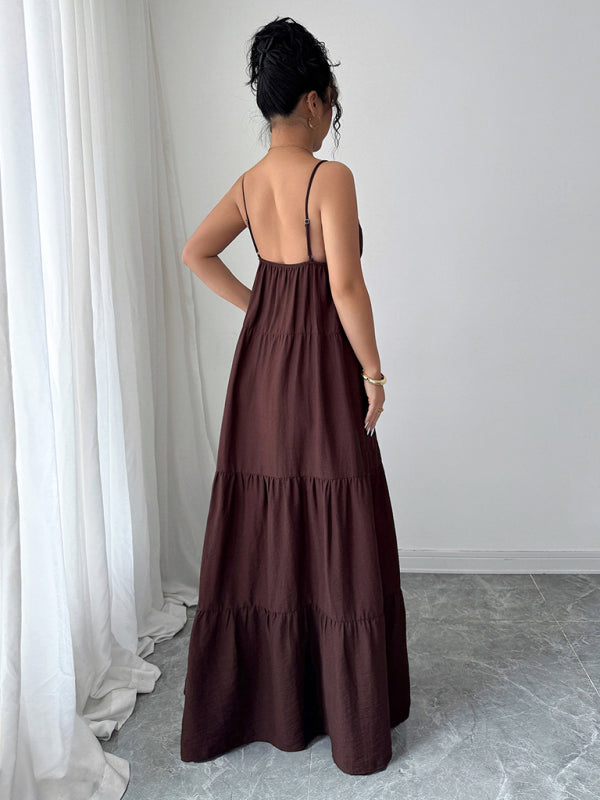 Woman wearing a brown tiered dress in a minimalistic room with white curtains and light gray floor.