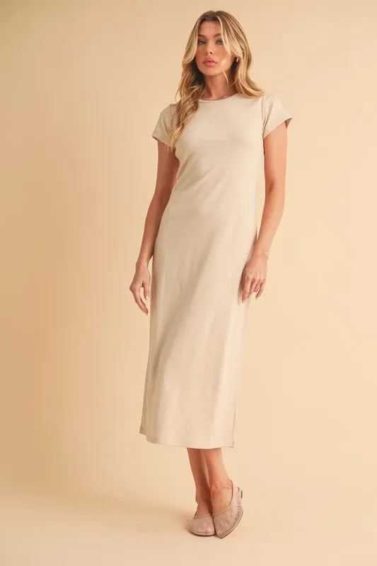 Woman wearing beige short sleeve maxi dress standing against a neutral background
