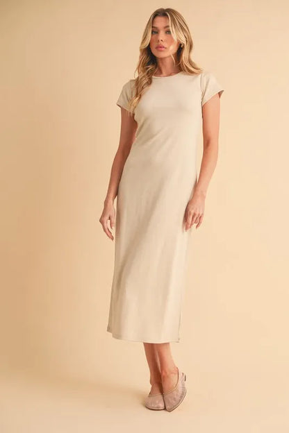 Woman wearing beige short sleeve maxi dress standing against a neutral background
