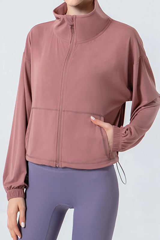 "Woman wearing a dusty rose zip-up sports jacket"

