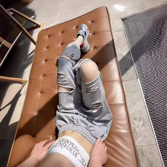 Woman wearing gray ripped jogger sweatpants with casual streetwear style

