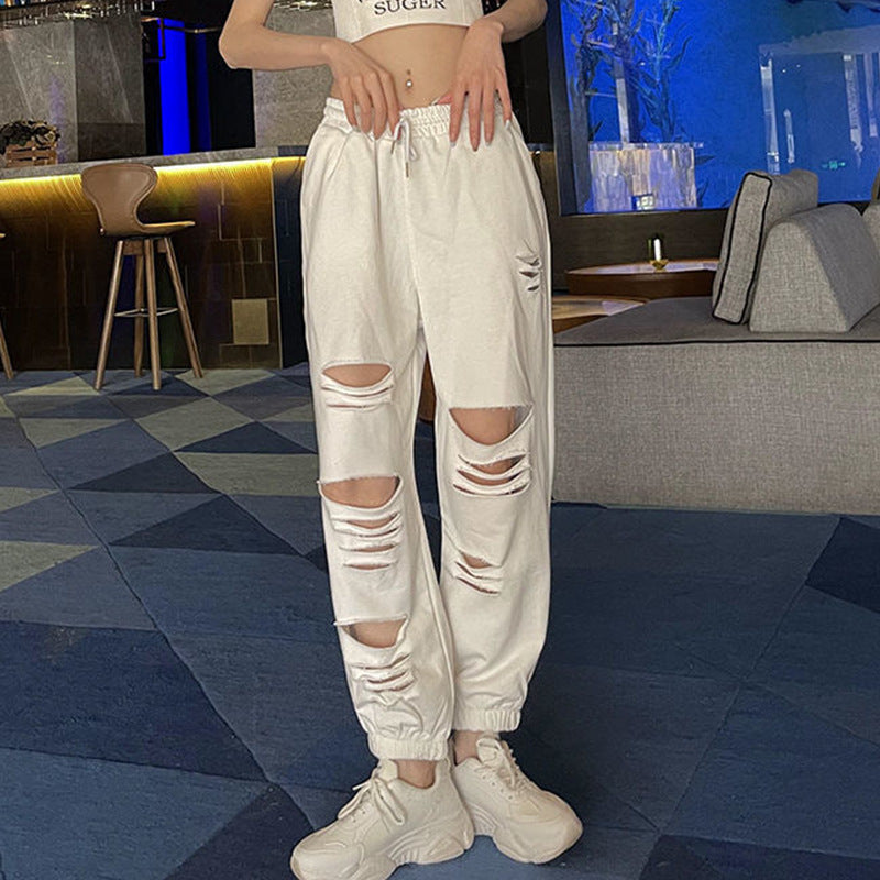 Woman wearing white torn jogger sweatpants with a bold and trendy look

