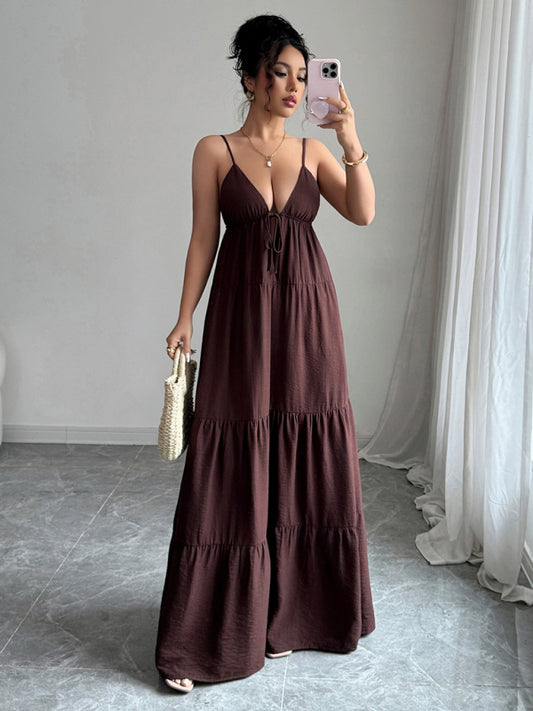Woman in a long brown dress taking a mirror selfie in a room with white curtains.