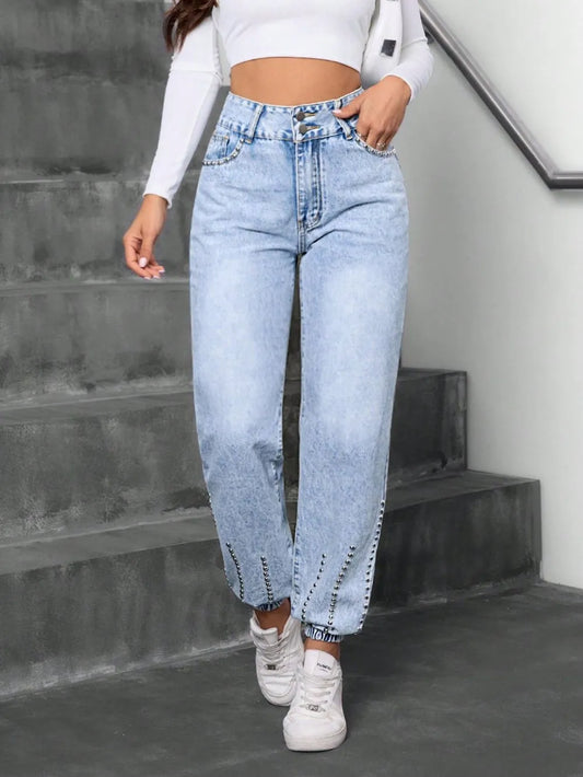 Women's light blue acid wash high waist barrel leg jeans with silver rhinestone stud detail on waistband and hem